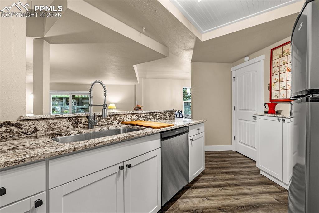 1679 Deer Creek Road Monument, CO 80132 - Photo 15 of 21 Kitchen featuring light stone counters, white cabinets, dark wood finished floors, and stainless steel appliances