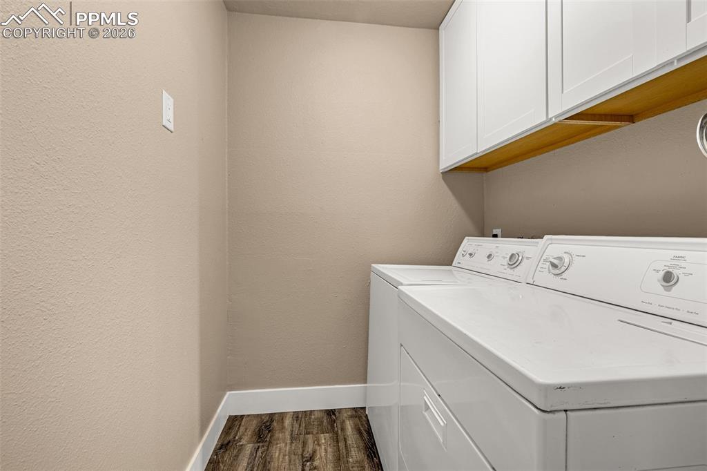 1679 Deer Creek Road Monument, CO 80132 - Photo 16 of 21 Laundry room featuring cabinet space, dark wood-style floors, separate washer and dryer, and a textured wall