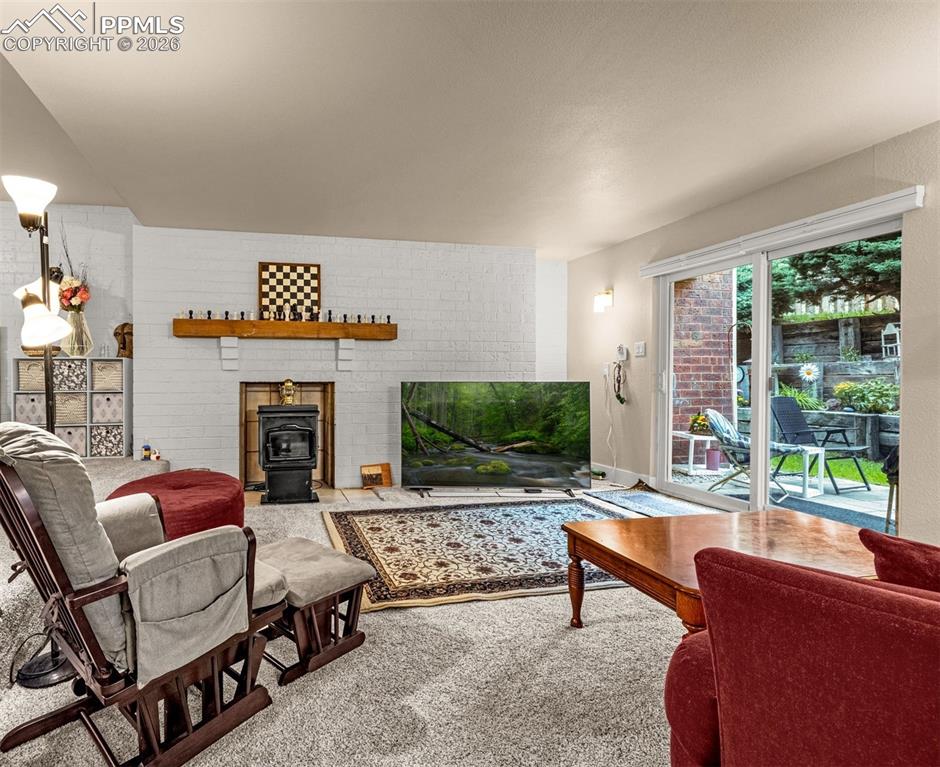 1679 Deer Creek Road Monument, CO 80132 - Photo 10 of 21 Carpeted living area with a wood stove and brick wall