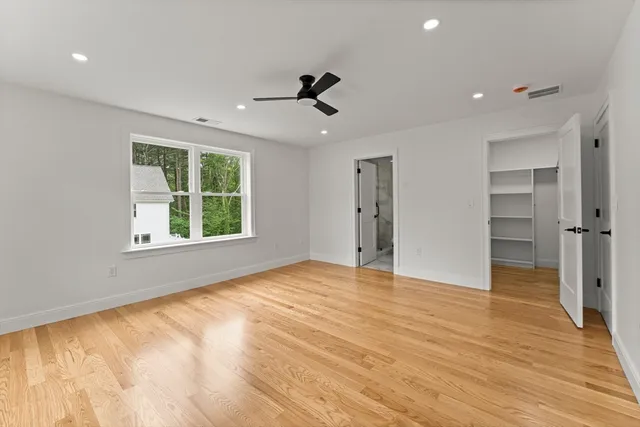 a view of an empty room with a window and wooden floor