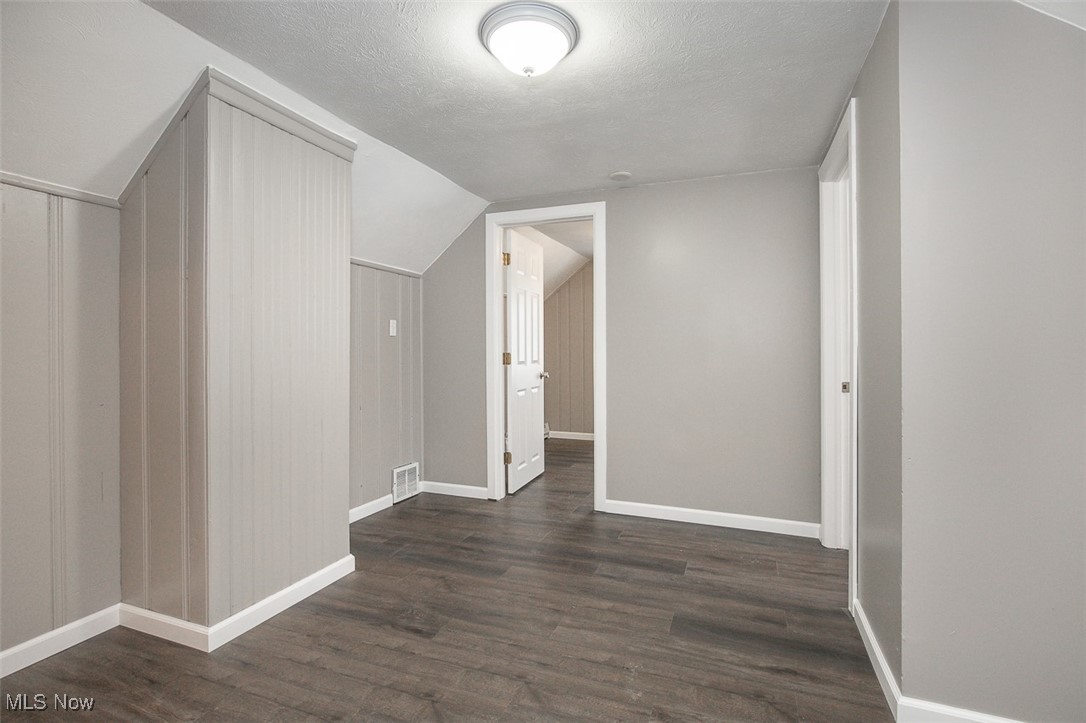 12328 Granger Road Cleveland, OH 44125 - Photo 23 of 37 Bonus room featuring dark wood finished floors, a textured ceiling, and vaulted ceiling