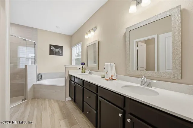 a spacious bathroom with a bathtub double sink and mirror