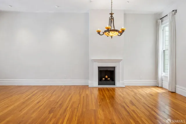 a view of a livingroom with a fireplace wooden floor and chandelier