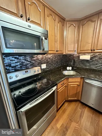a kitchen with granite countertop a sink a stove and cabinets