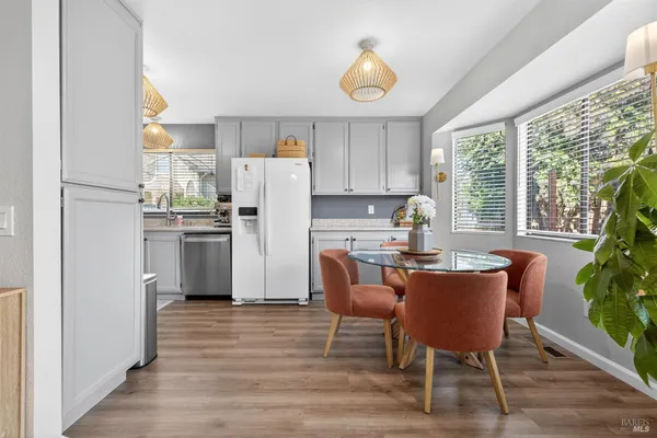 a kitchen with stainless steel appliances a dining table chairs refrigerator and sink