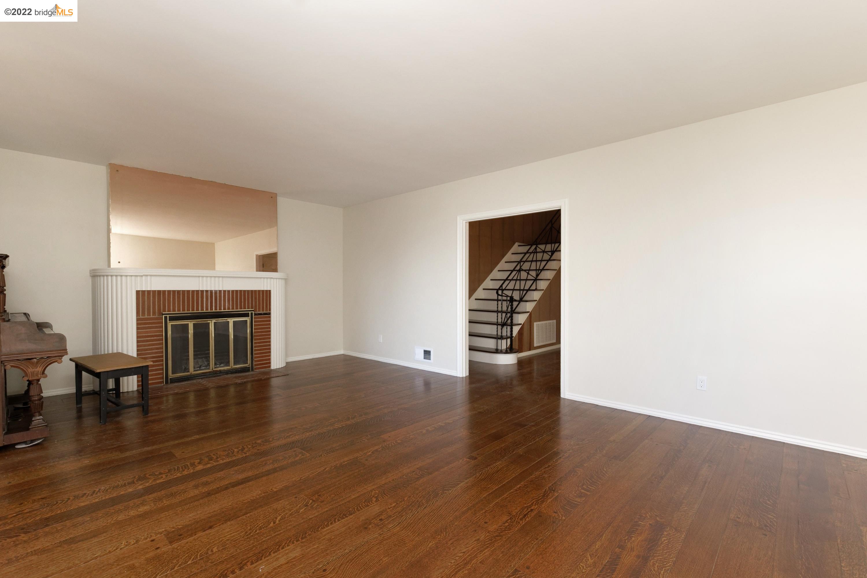 920 Spruce Street Berkeley, CA 94707 - Photo 9 of 36 an empty room with wooden floor fireplace and windows