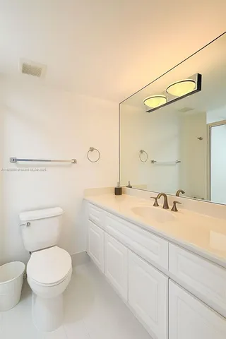 a bathroom with a granite countertop toilet sink and mirror