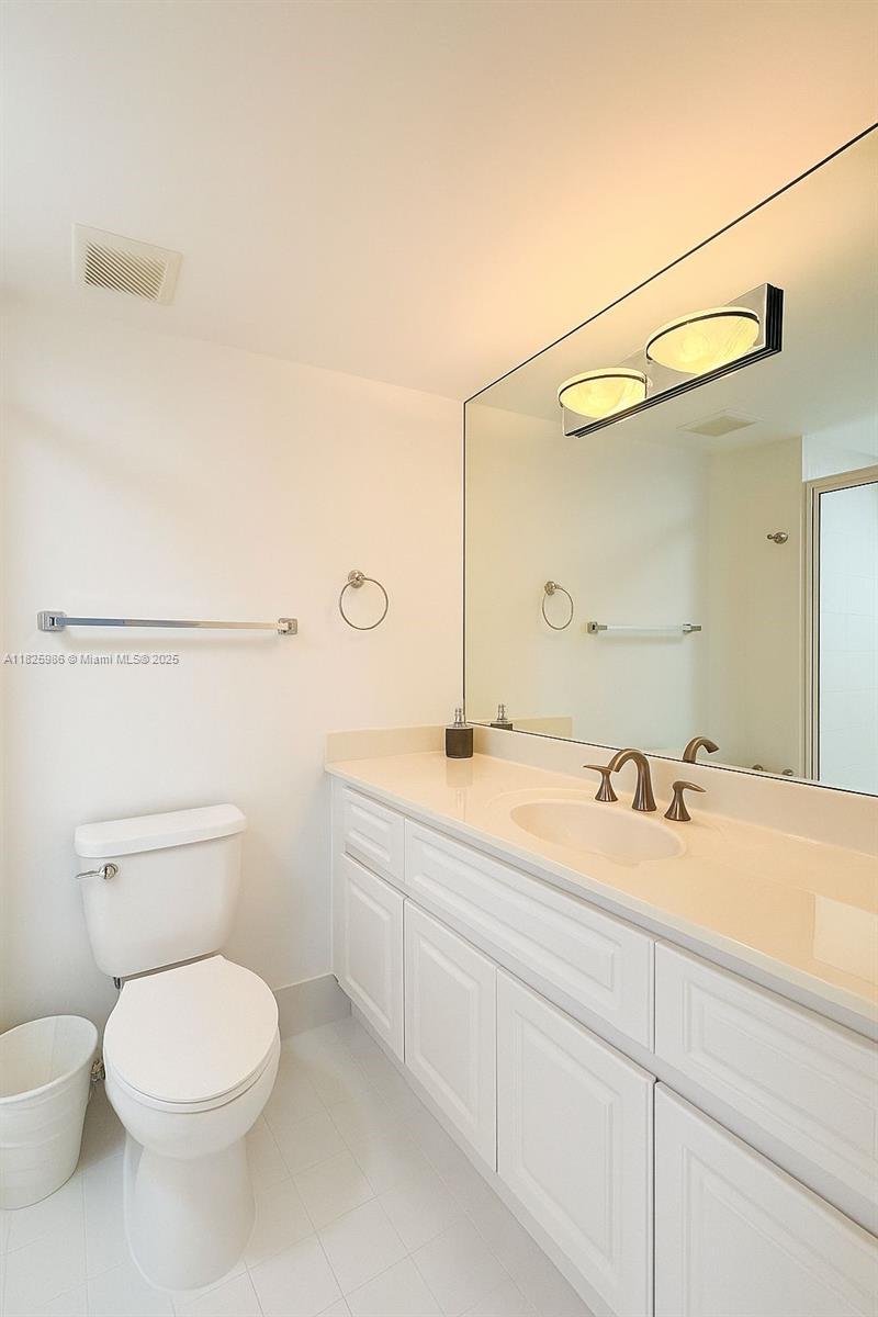 6301 Collins Avenue, Unit 1005 Miami Beach, FL 33141 - Photo 13 of 35 a bathroom with a granite countertop toilet sink and mirror