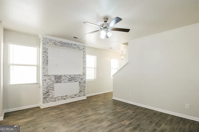 a view of a livingroom with wooden floor window and a ceiling fan