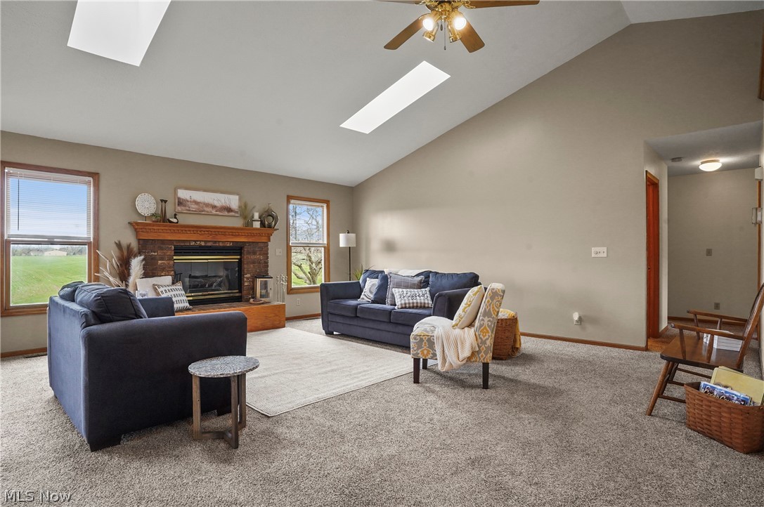 1106 Apple Ridge Road Clinton, OH 44216 - Photo 8 of 27 Living room with a skylight, ceiling fan, light colored carpet, and a brick fireplace