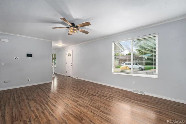 a view of a room with wooden floor kitchen view and a window