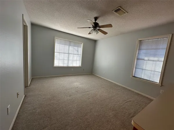 an empty room with windows and fan