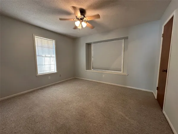 an empty room with windows and fan