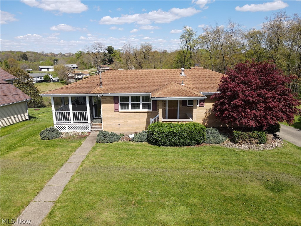 View of front facade with a front lawn and a sunroom