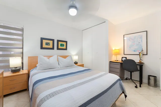 a bedroom with a bed and a potted plant on a dresser