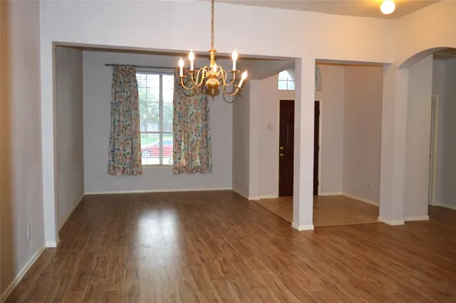 a view of a room with wooden floor chandelier and glass door