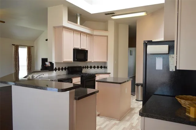 a kitchen with stainless steel appliances granite countertop a sink and a refrigerator
