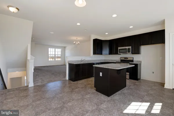 a kitchen with stainless steel appliances granite countertop a sink a stove a refrigerator a center island and a window