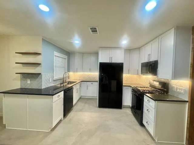 a kitchen with stainless steel appliances granite countertop a refrigerator a stove a sink and a microwave