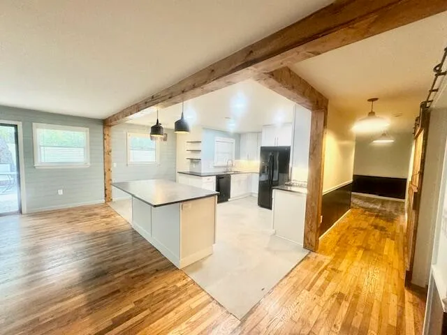 a large white kitchen with wooden floors and sink
