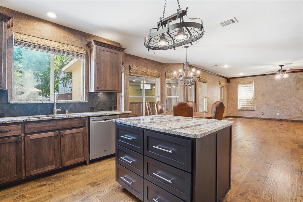 2133 Rustic Ridge Drive Keller, TX 76248 - Photo 39 of 40 Kitchen featuring a kitchen island, light wood-type flooring, light stone countertops, open floor plan, and dishwasher