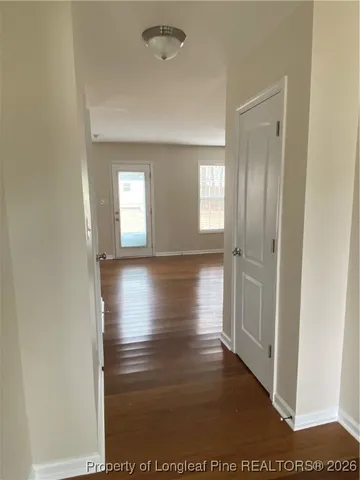 a view of hallway with window and wooden floor