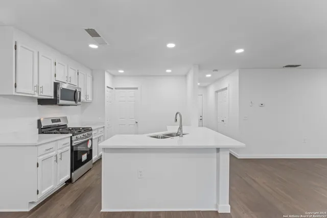 a kitchen with stainless steel appliances granite countertop a sink a stove a microwave a counter top space and cabinets