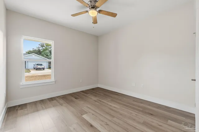 an empty room with wooden floor and ceiling fan