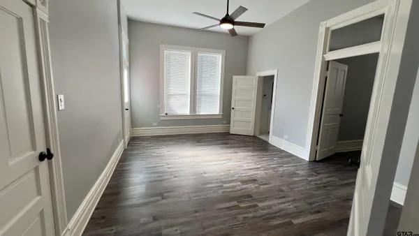 an empty room with wooden floor and a ceiling fan