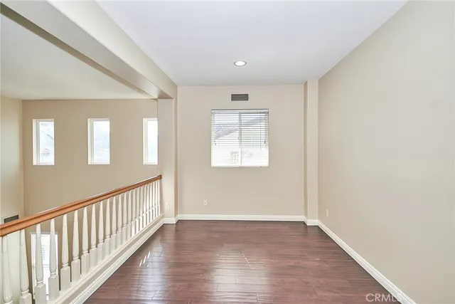 an empty room with wooden floor chandelier fan and windows