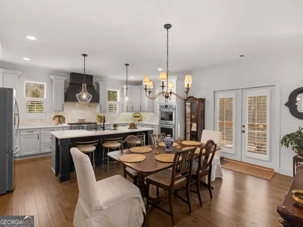 a view of a dining room and livingroom with furniture wooden floor a rug a fireplace and a chandelier