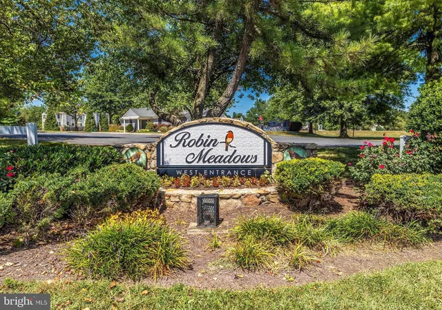 a sign board with a house in the background