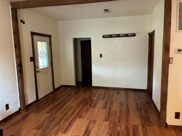an empty room with wooden floor and a mirror