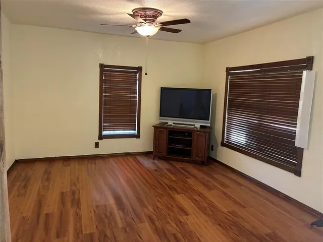 a view of room with hardwood floor and a ceiling fan