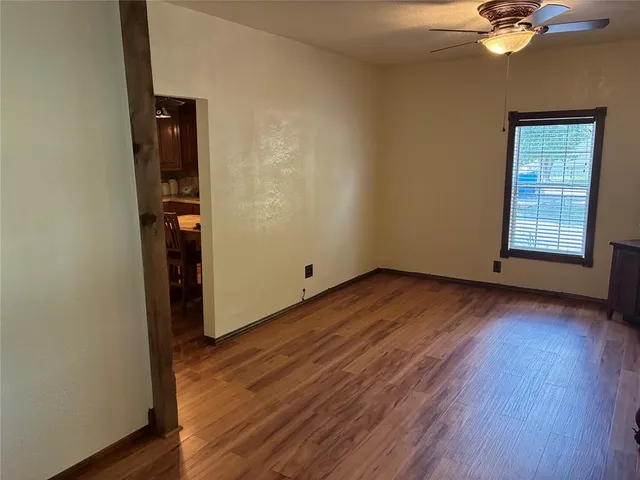 an empty room with wooden floor closet and windows