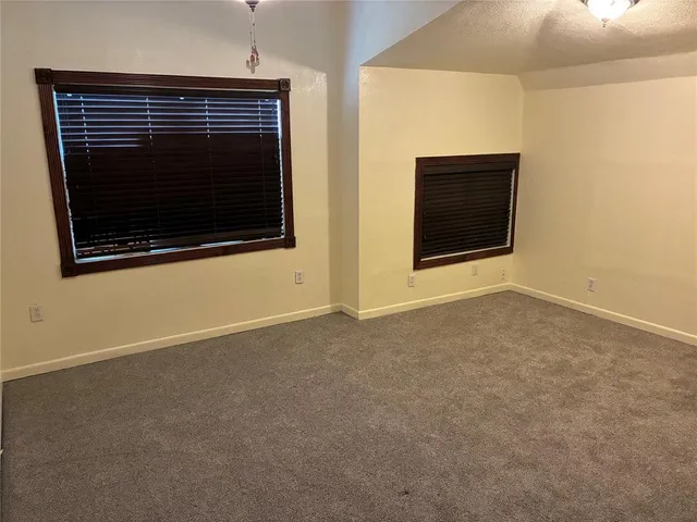 a view of an empty room with wooden floor and a fireplace