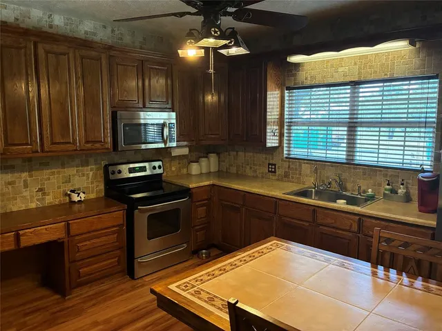 a kitchen with stainless steel appliances a sink a stove a microwave cabinets and a window