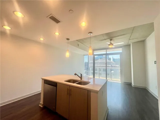 a kitchen with stainless steel appliances kitchen island a sink dishwasher a refrigerator and a stove with wooden floor