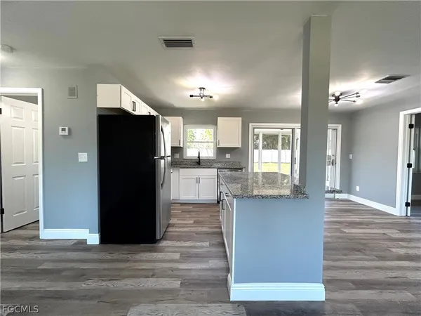 a view of a kitchen with refrigerator and wooden floor