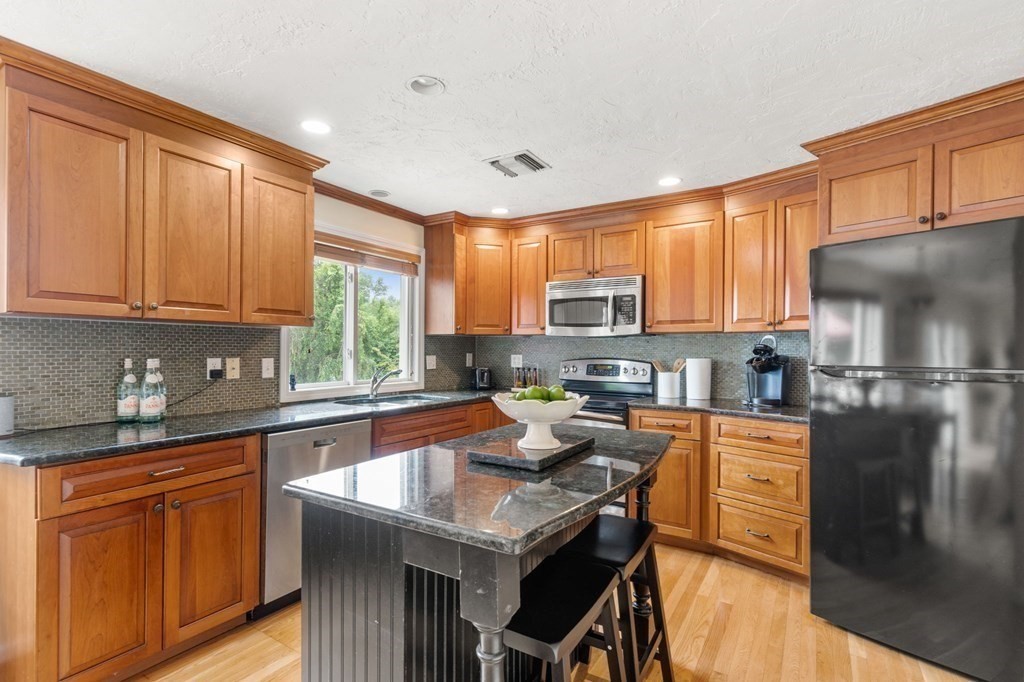 96 Bridge Street Medfield, MA 02052 - Photo 6 of 41 a kitchen with stainless steel appliances granite countertop a refrigerator a sink dishwasher a stove and white cabinets with wooden floor