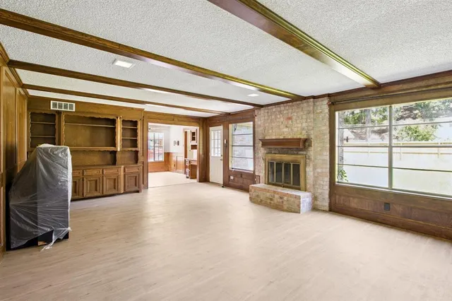 a view of an empty room with a fireplace and a window