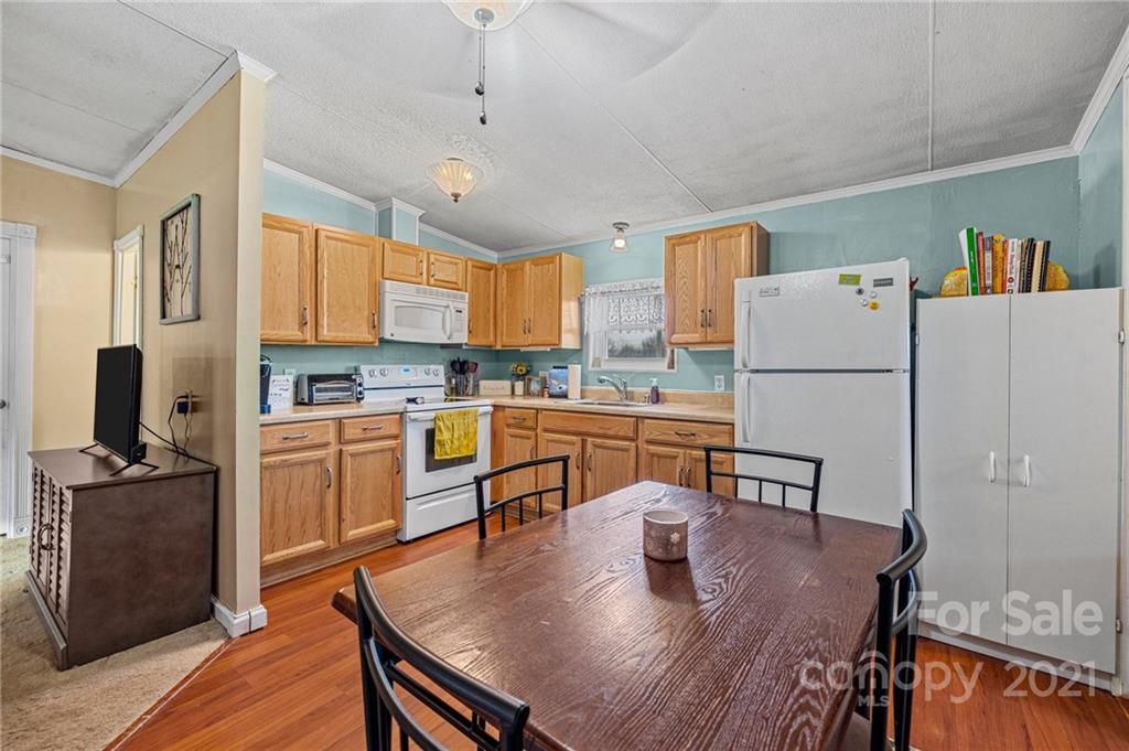 4507 Morgan Mill Road Monroe, NC 28110 - Photo 13 of 33 a kitchen with granite countertop a refrigerator a stove a sink a dining table and chairs with wooden floor