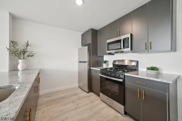 a kitchen with stainless steel appliances granite countertop a stove a sink and a refrigerator