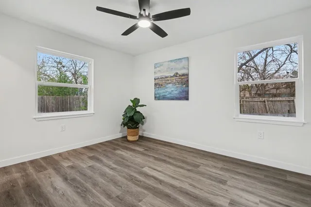 an empty room with wooden floor and a ceiling fan