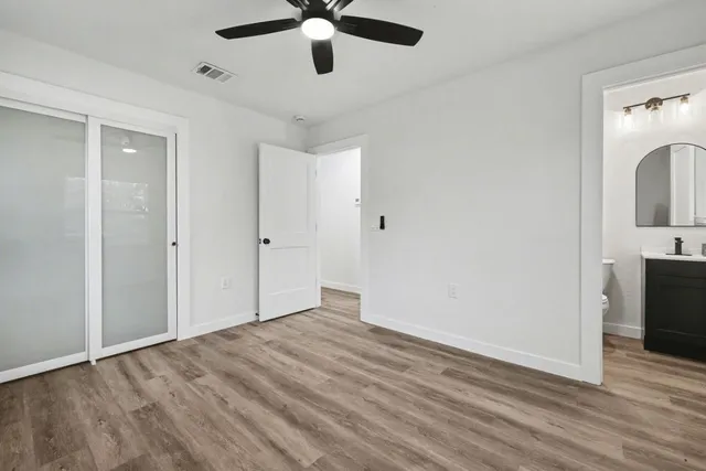 a view of empty room with wooden floor and fan