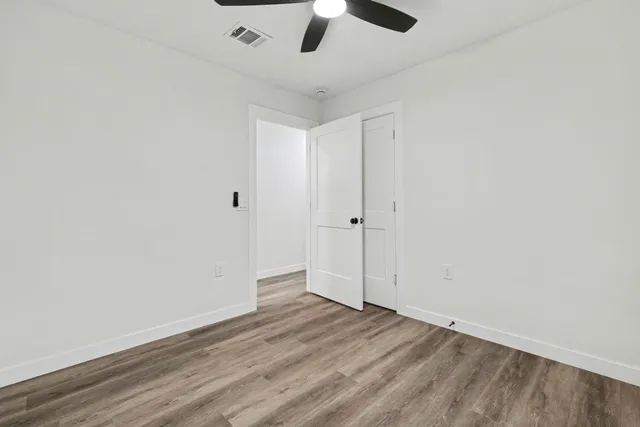 a view of an empty room with window and wooden floor