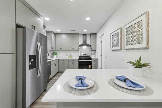 a kitchen with stainless steel appliances granite countertop a refrigerator sink and white cabinets