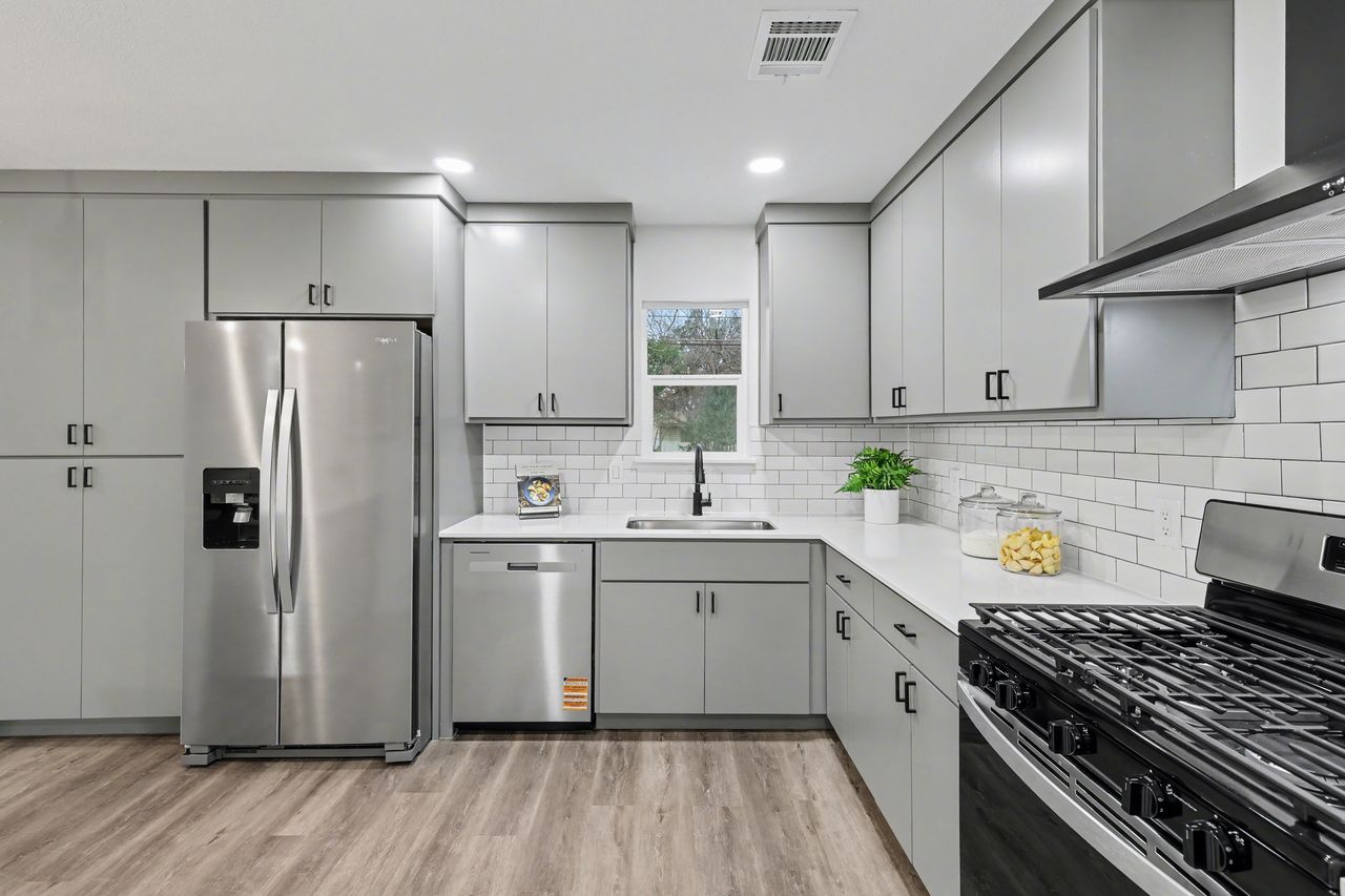 2103 Fordham Cove Austin, TX 78723 - Photo 9 of 36 a kitchen with a sink a refrigerator and white cabinets