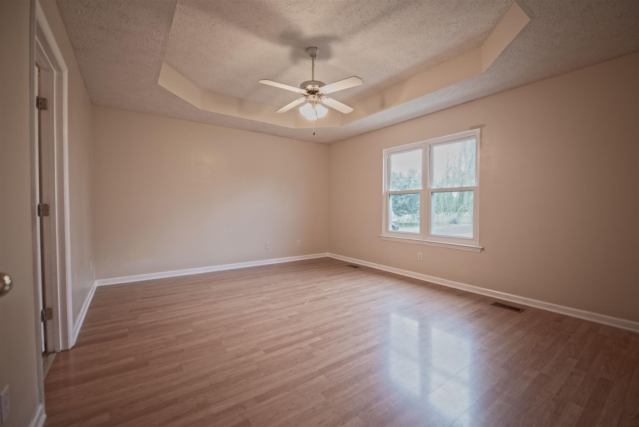 7500 Joe Rowlin Road Christiana, TN 37037 - Photo 14 of 22 an empty room with wooden floor chandelier fan and windows
