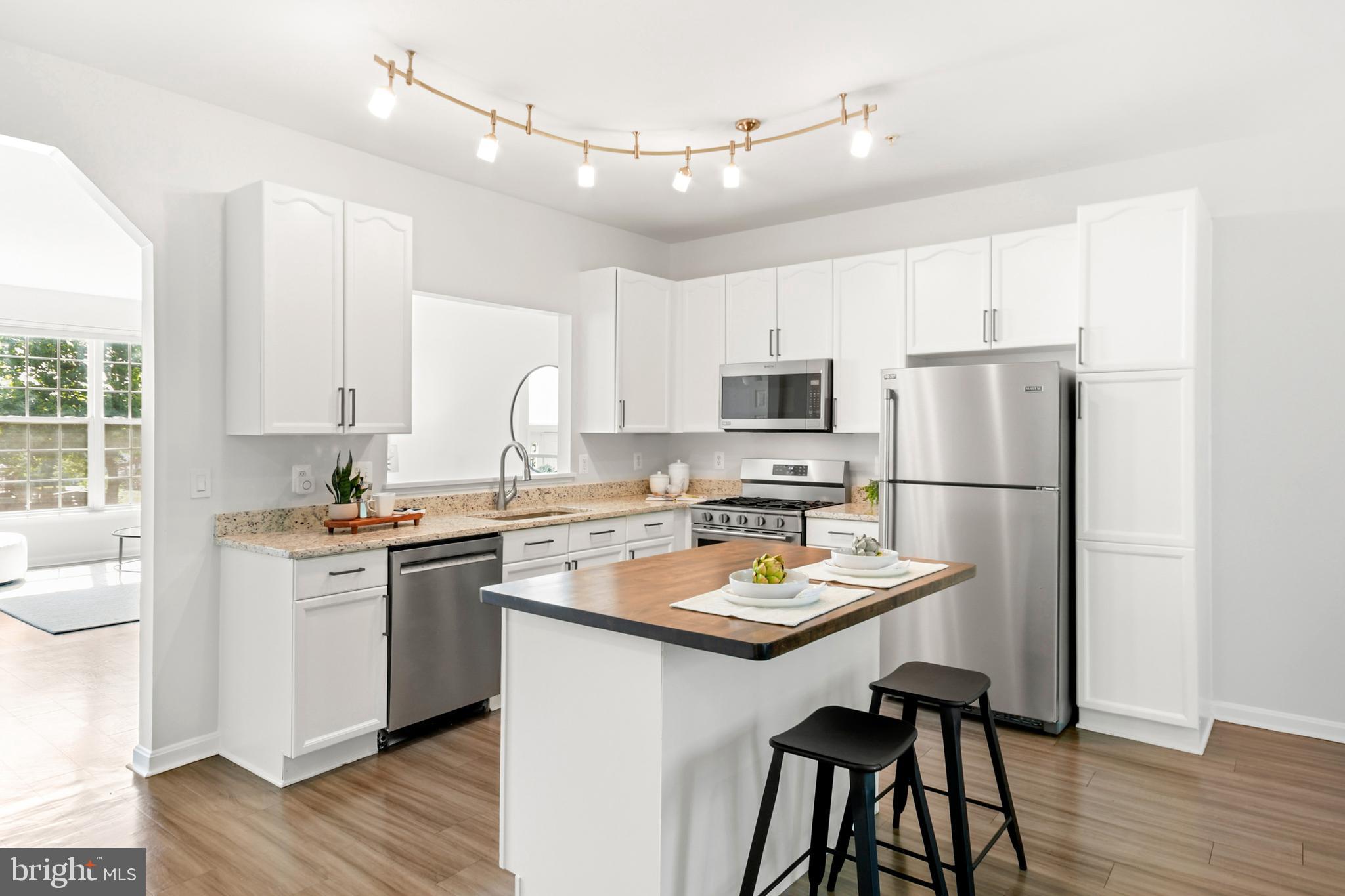 6577 Duncan Place Frederick, MD 21703 - Photo 5 of 10 a kitchen with a stove a sink dishwasher a refrigerator with white cabinets and wooden floor